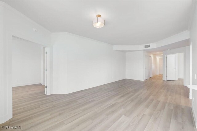 spare room featuring light wood-style floors, visible vents, and crown molding