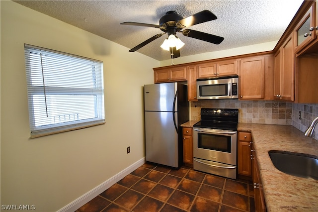 kitchen with stainless steel appliances, ceiling fan, tasteful backsplash, dark tile flooring, and sink