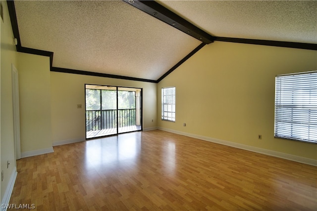 spare room featuring a textured ceiling, lofted ceiling with beams, and hardwood / wood-style floors