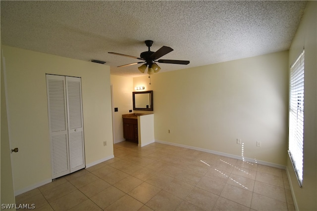 unfurnished bedroom with a textured ceiling, a closet, ceiling fan, and light tile floors