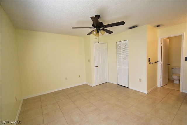 unfurnished bedroom featuring a textured ceiling, connected bathroom, ceiling fan, and light tile floors