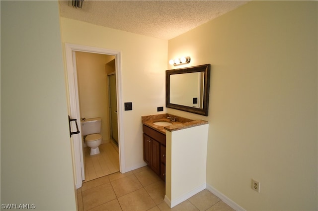 bathroom featuring tile flooring, a textured ceiling, toilet, and large vanity