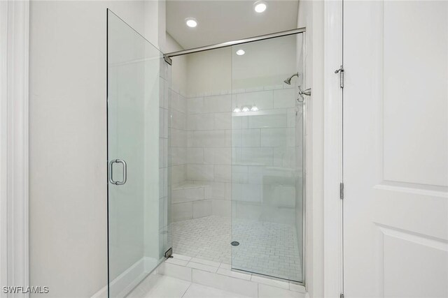 bathroom with a shower with door and tile patterned flooring