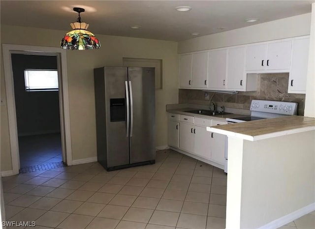 kitchen with kitchen peninsula, stainless steel fridge, light tile flooring, white cabinets, and tasteful backsplash