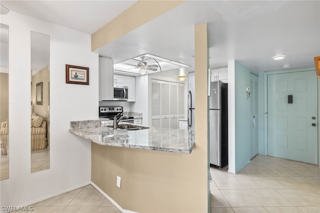 kitchen with light stone counters, stainless steel appliances, white cabinetry, ceiling fan, and sink