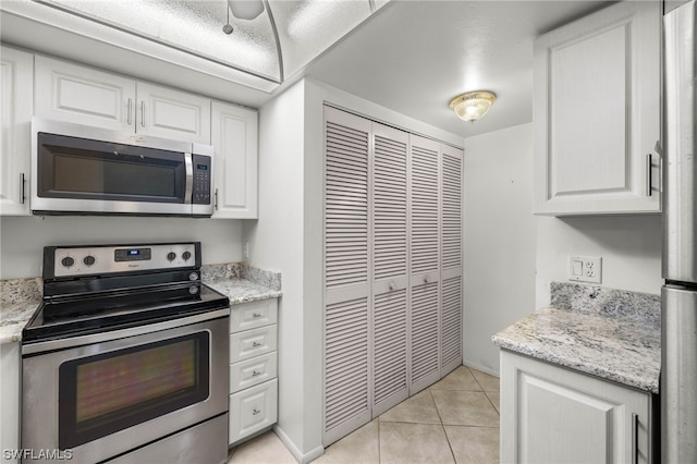 kitchen featuring white cabinets, appliances with stainless steel finishes, light stone countertops, and light tile patterned floors