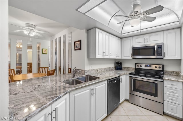 kitchen featuring sink, white cabinets, light tile patterned flooring, light stone countertops, and appliances with stainless steel finishes