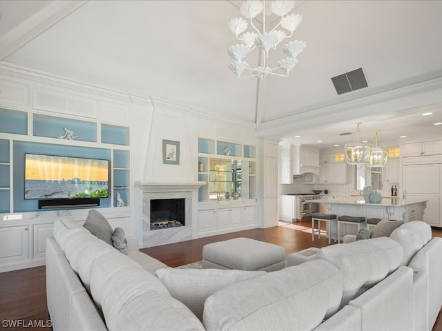 living room featuring built in shelves, crown molding, a high end fireplace, and dark hardwood / wood-style floors