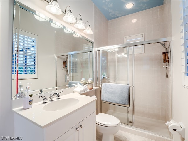 bathroom with tile floors, toilet, a shower with shower door, and vanity with extensive cabinet space