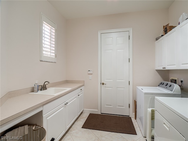 washroom with cabinets, sink, light tile floors, washer hookup, and washing machine and clothes dryer