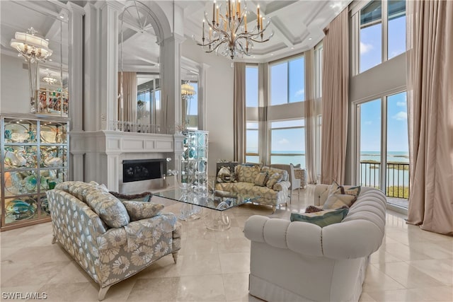 tiled living room with a high ceiling, coffered ceiling, a water view, a chandelier, and ornate columns