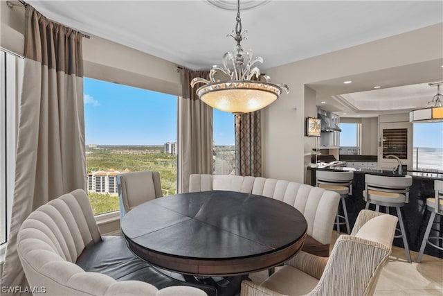 tiled dining space with an inviting chandelier, plenty of natural light, and a tray ceiling