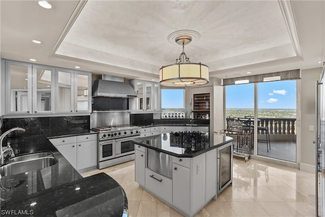 kitchen featuring range with two ovens, a wealth of natural light, sink, and wall chimney range hood