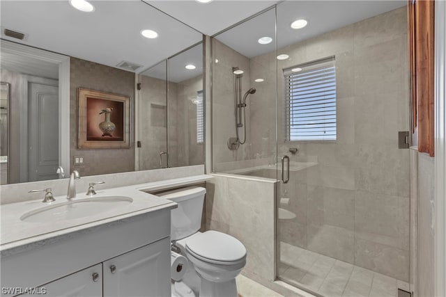 bathroom with a shower with shower door, vanity with extensive cabinet space, and toilet