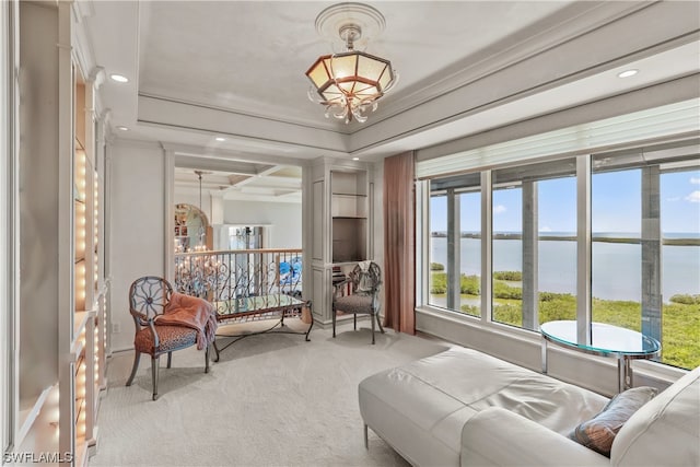 sitting room with a water view, a raised ceiling, ornamental molding, and light colored carpet