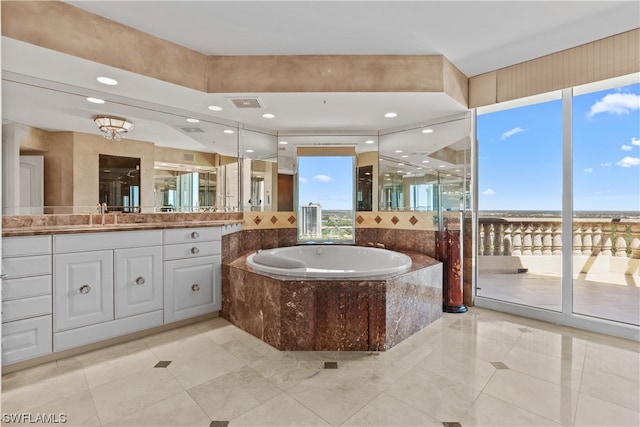 bathroom featuring tile flooring, vanity with extensive cabinet space, and tiled tub