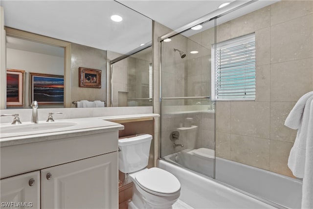 full bathroom with shower / bath combination with glass door, toilet, and vanity with extensive cabinet space