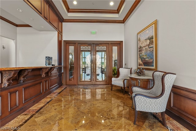 tiled entrance foyer featuring a raised ceiling, french doors, and ornamental molding