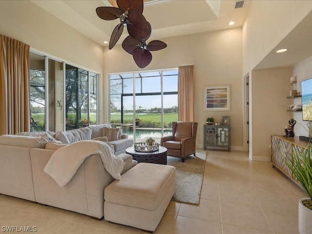 living room featuring a high ceiling, ceiling fan, light tile patterned floors, and plenty of natural light