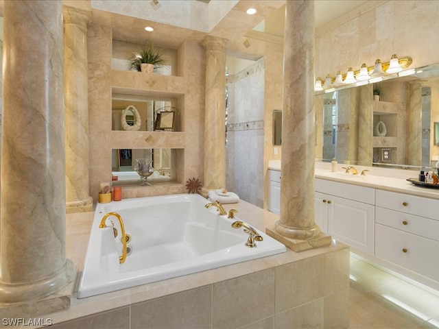 bathroom featuring decorative columns, a relaxing tiled tub, and vanity