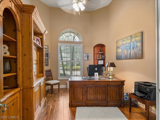 office area with light hardwood / wood-style flooring, ceiling fan, and a towering ceiling