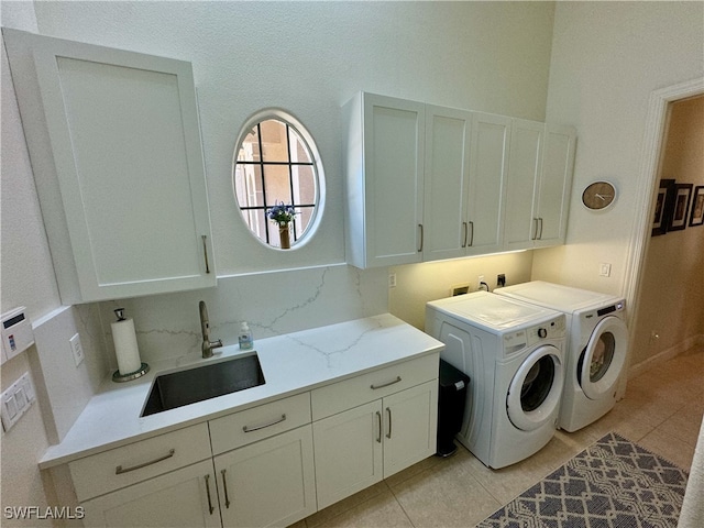 clothes washing area featuring light tile patterned floors, washing machine and clothes dryer, cabinets, and sink