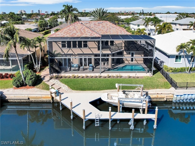 back of property featuring glass enclosure, a water view, a yard, and a patio area