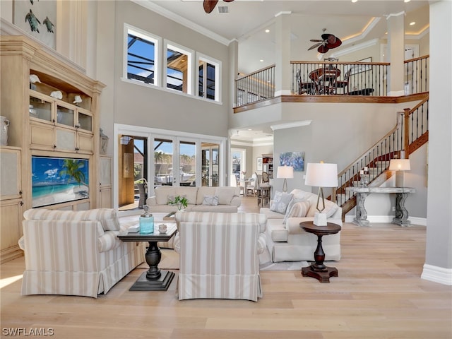 living room with light wood-type flooring, crown molding, a high ceiling, ceiling fan, and french doors