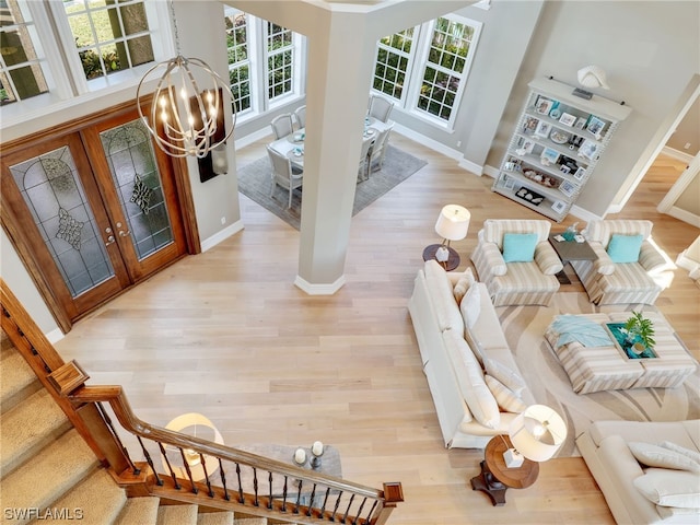 living room featuring light hardwood / wood-style flooring, a towering ceiling, and a notable chandelier