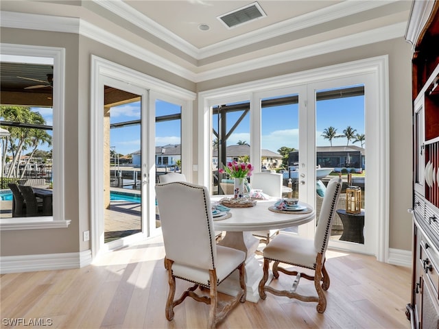 dining room featuring french doors, light hardwood / wood-style flooring, and crown molding