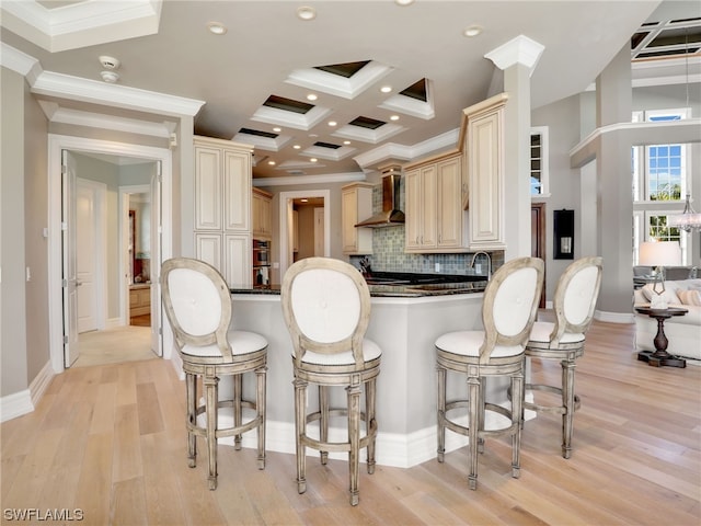 kitchen with wall chimney exhaust hood, light wood-type flooring, kitchen peninsula, and decorative backsplash