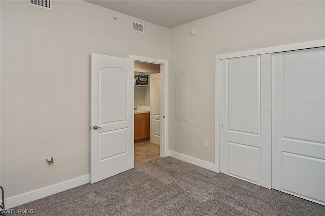 unfurnished bedroom featuring dark carpet and a closet