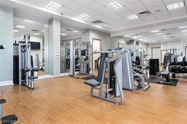 workout area with light wood-type flooring and a paneled ceiling