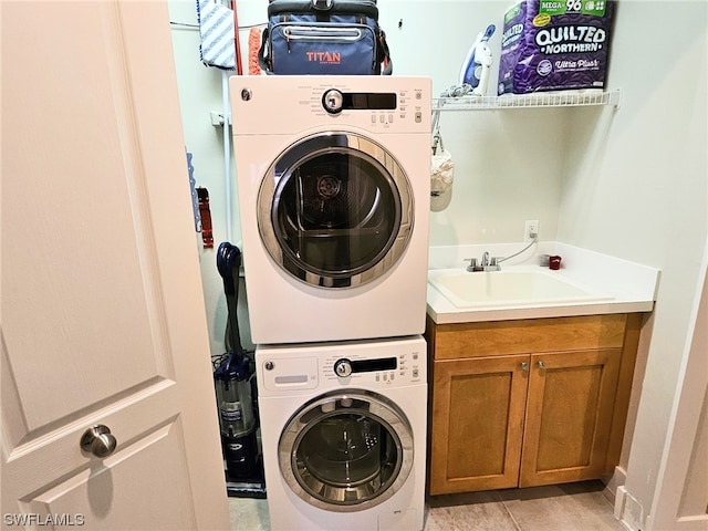 clothes washing area with cabinets, stacked washing maching and dryer, sink, and light tile patterned floors