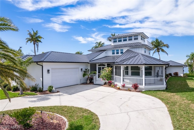 view of front of house featuring a front lawn, covered porch, and a garage