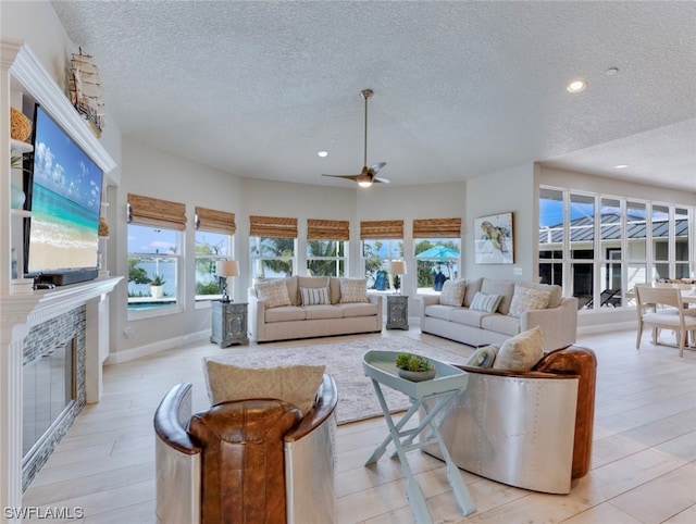 living room with a textured ceiling, ceiling fan, and a wealth of natural light