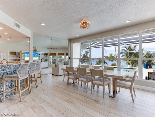 dining space featuring a textured ceiling and light wood-type flooring