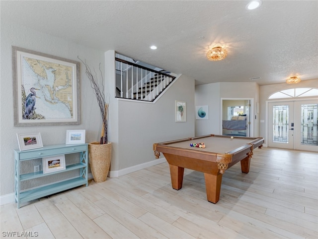 recreation room featuring a textured ceiling, pool table, french doors, and light wood-type flooring