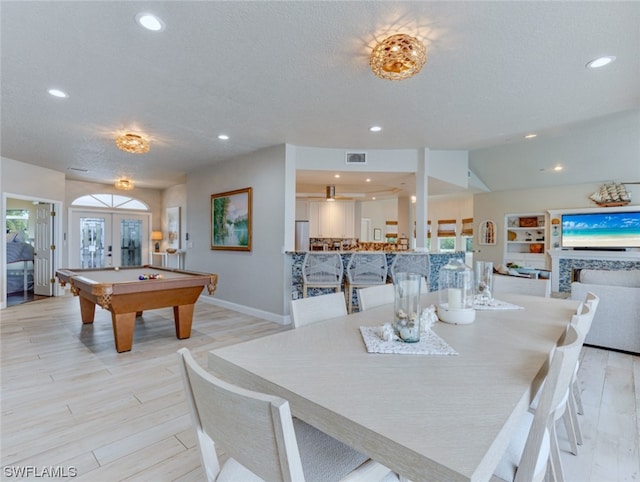 dining space with french doors, a textured ceiling, billiards, and light wood-type flooring