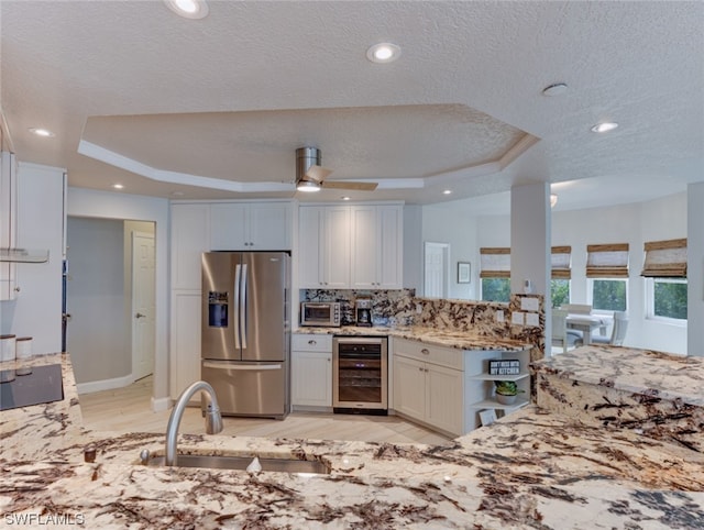 kitchen with ceiling fan, sink, wine cooler, a raised ceiling, and stainless steel refrigerator with ice dispenser