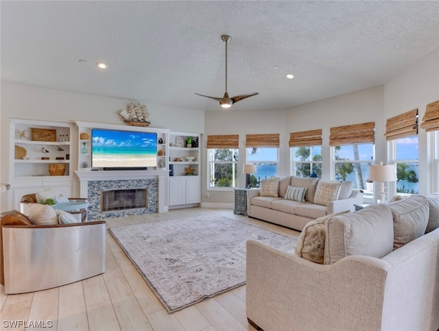 living room with light hardwood / wood-style floors, a textured ceiling, ceiling fan, and built in shelves