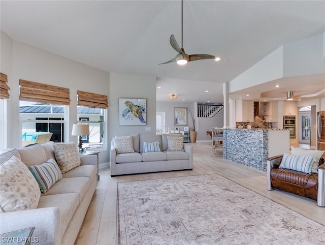 living room featuring lofted ceiling, ceiling fan, and light wood-type flooring