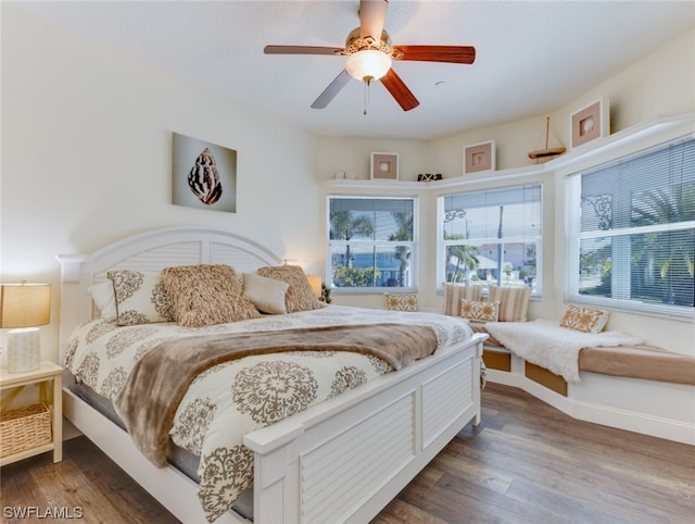 bedroom featuring dark hardwood / wood-style flooring, ceiling fan, and multiple windows