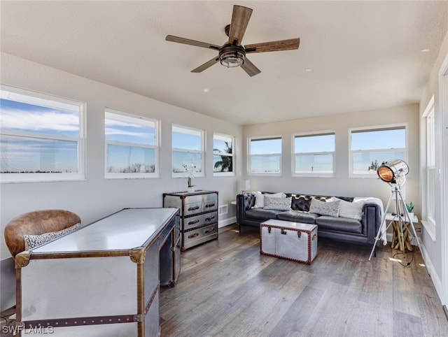 living room with ceiling fan, dark wood-type flooring, and a wealth of natural light