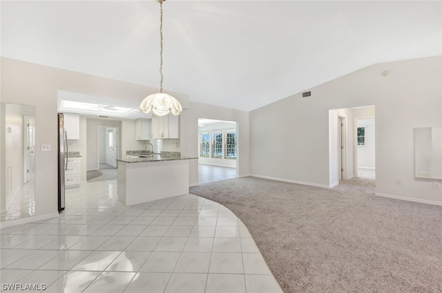 unfurnished room with a notable chandelier, lofted ceiling, sink, and light colored carpet