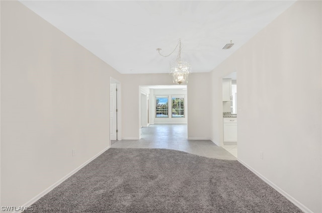 empty room with light colored carpet and a chandelier