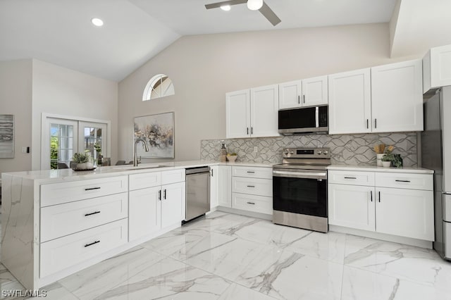 kitchen featuring high vaulted ceiling, backsplash, stainless steel appliances, kitchen peninsula, and ceiling fan