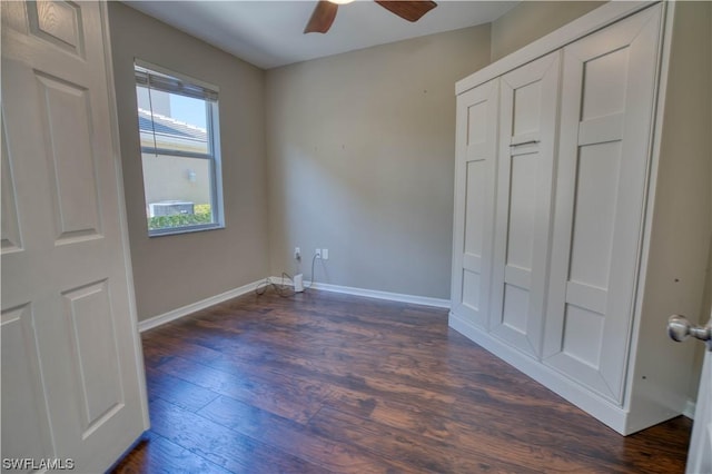 unfurnished bedroom with dark wood-type flooring, a closet, and ceiling fan