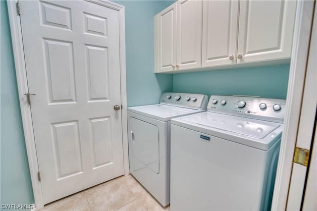 laundry area with cabinets, washing machine and dryer, and light tile patterned floors