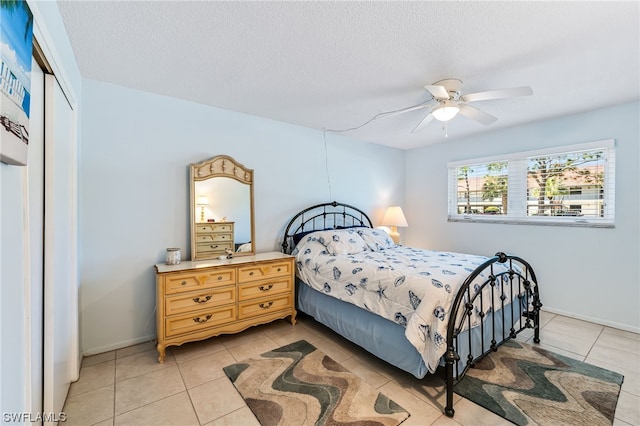 bedroom featuring light tile floors, a closet, ceiling fan, and a textured ceiling